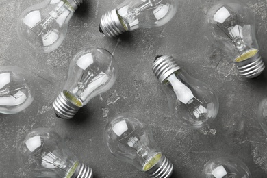 New incandescent lamp bulbs on grey stone surface, flat lay