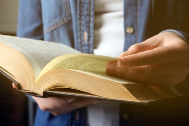 Photo of Woman reading old holy Bible on blurred background, closeup
