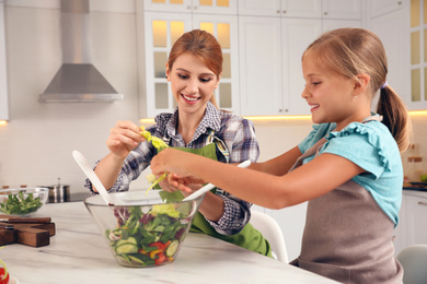 Mother and daughter cooking salad together in kitchen