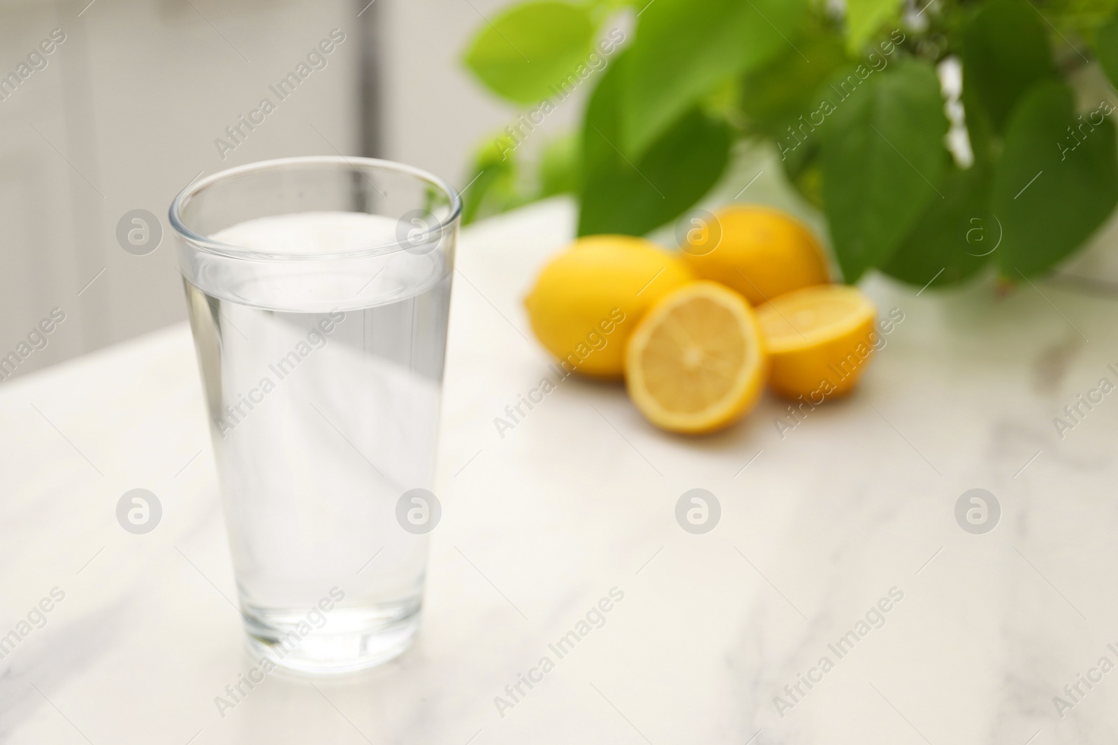 Photo of Glass with clear water on white marble table in kitchen