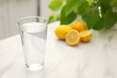 Glass with clear water on white marble table in kitchen