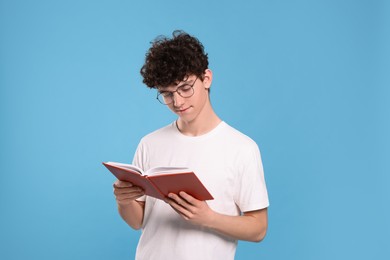 Photo of Teenage boy reading book on light blue background