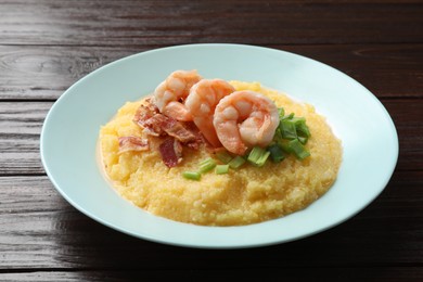 Photo of Plate with fresh tasty shrimps, bacon and grits on dark wooden table