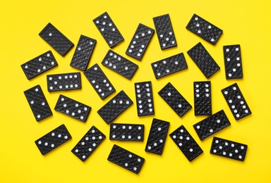 Black domino tiles on yellow background, flat lay