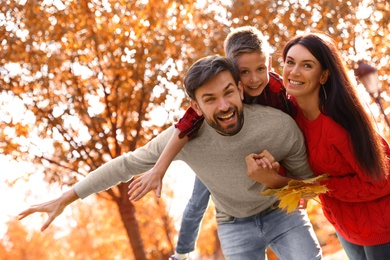 Photo of Happy family with son spending time in park. Autumn walk