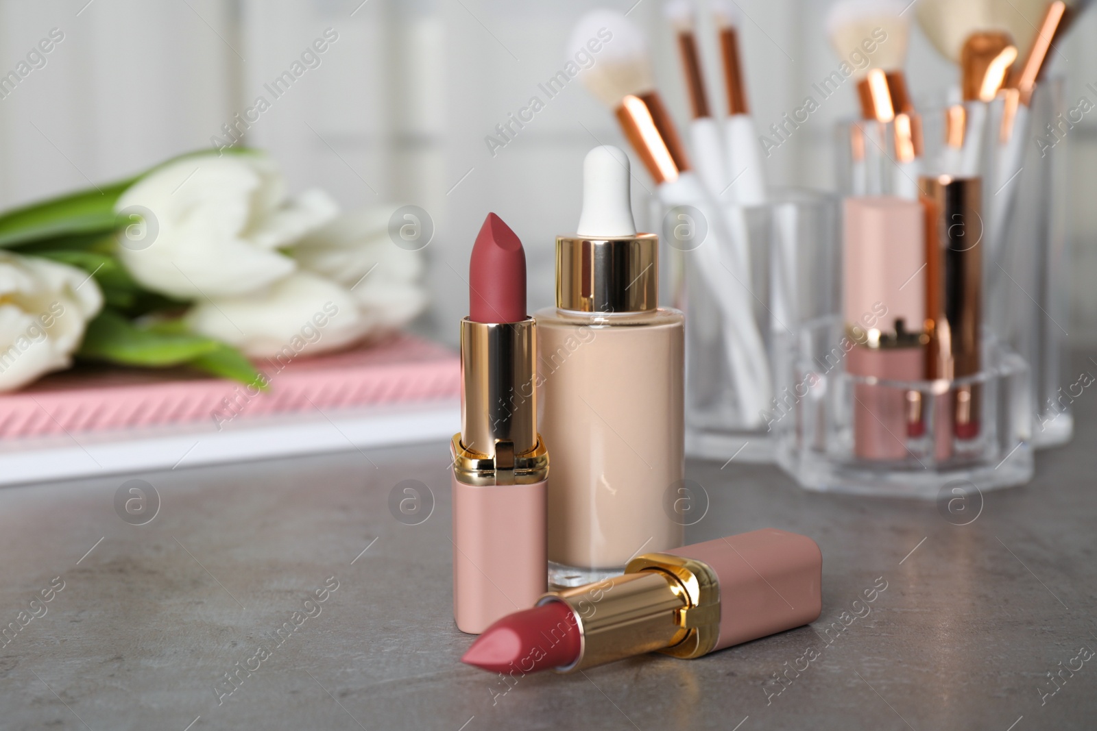Photo of Decorative cosmetic products and makeup brushes on grey table