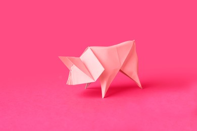 Photo of Origami art. Handmade bright paper pig on pink background