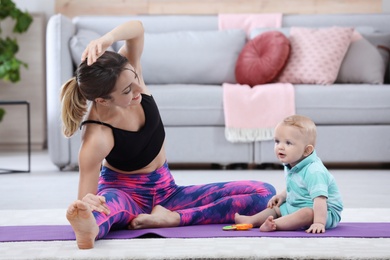 Young sportive woman doing exercise with her son at home. Fitness training