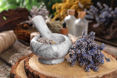 Mortar with pestle and lavender flowers on wooden table, closeup. Medicinal herbs