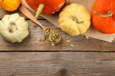 Photo of Spoon with peeled seeds and fresh pumpkins on wooden table, flat lay. Space for text