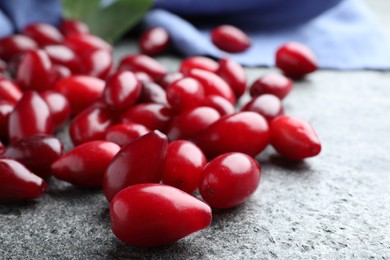 Photo of Pile of fresh ripe dogwood berries on grey table, closeup