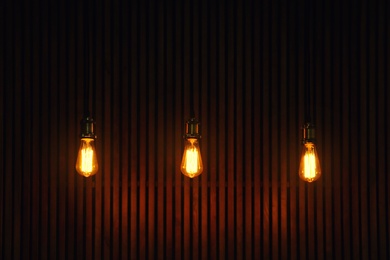 Photo of Pendant lamps with light bulbs on wooden background