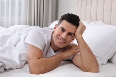 Photo of Happy man lying in bed at home