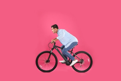 Photo of Handsome young man with modern bicycle on pink background