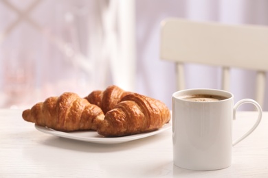 Cup of coffee and plate with croissants on table. Space for text