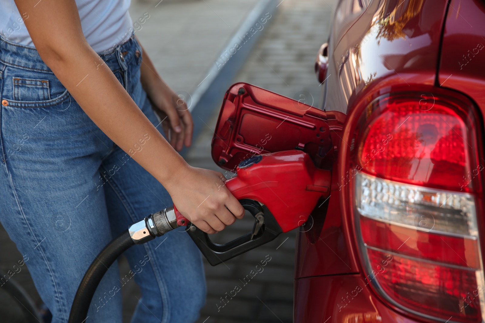 Photo of Young woman refueling car at self service gas station, closeup