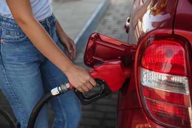 Photo of Young woman refueling car at self service gas station, closeup