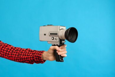 Woman with vintage video camera on light blue background, closeup of hand