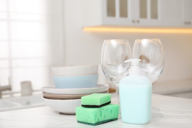 Set of clean dishes and cleaning product with sponge on table in stylish kitchen