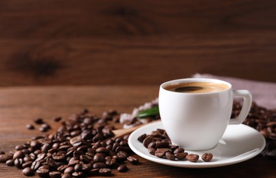 Cup of hot aromatic coffee and roasted beans on wooden table. Space for text