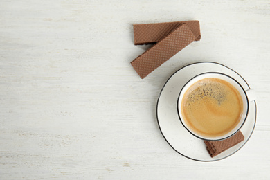 Breakfast with delicious wafers and coffee on white wooden table, flat lay. Space for text