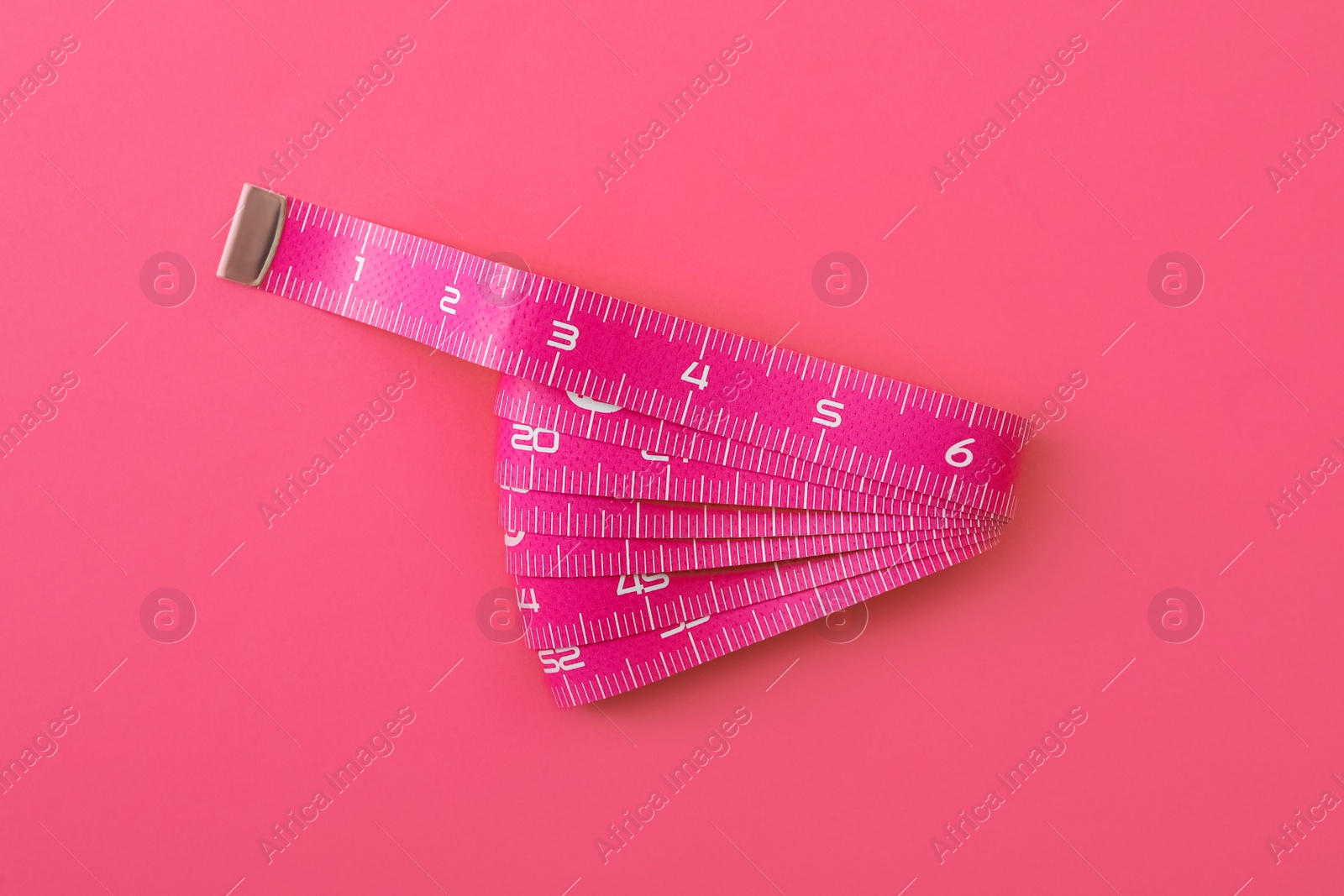Photo of Measuring tape on pink background, top view