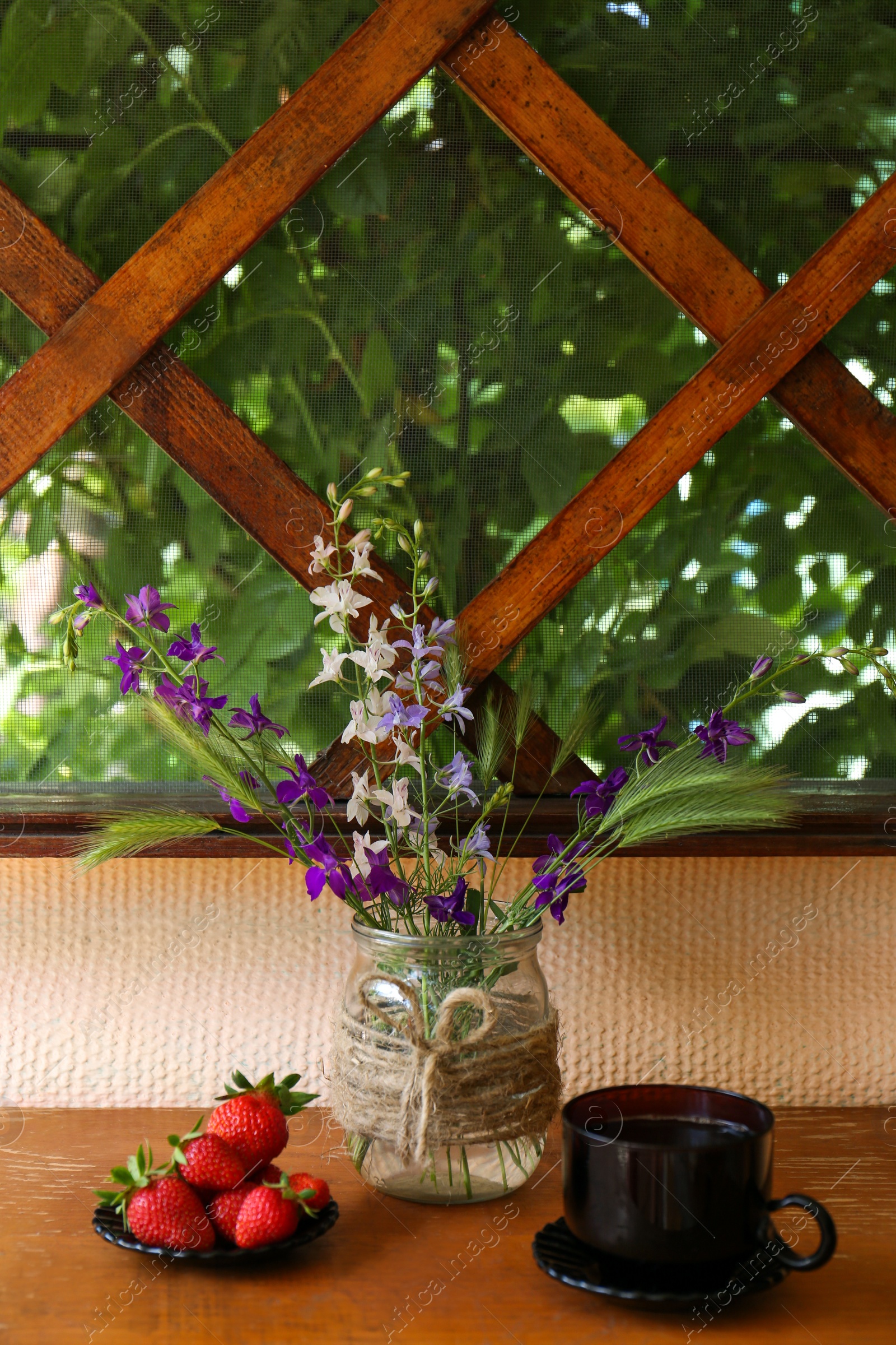 Photo of Bouquet of beautiful wildflowers, aromatic coffee and fresh strawberries on wooden table