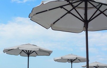 Photo of Beautiful white beach umbrellas against blue sky