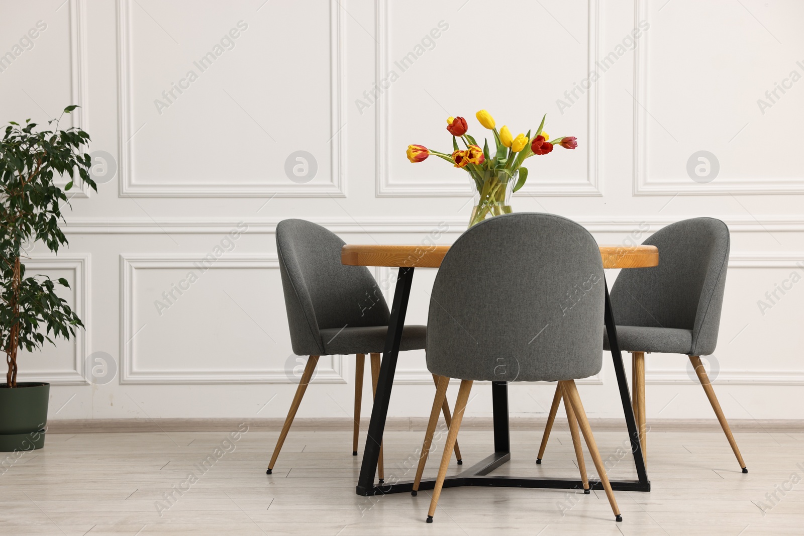 Photo of Stylish dining room interior with comfortable furniture and beautiful tulips