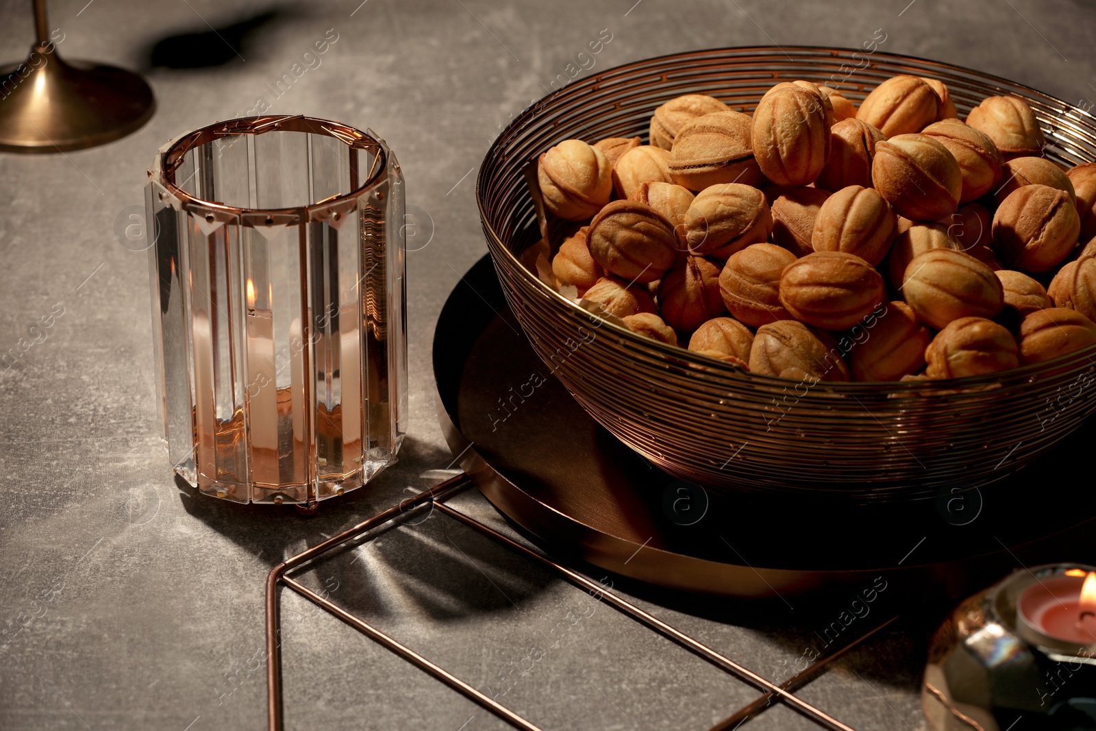 Photo of Delicious walnut shaped cookies and burning candles on grey table, closeup. Tasty pastry carrying nostalgic home atmosphere