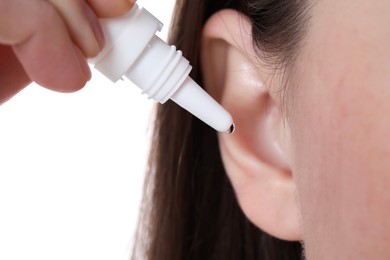 Woman using ear drops on white background, closeup
