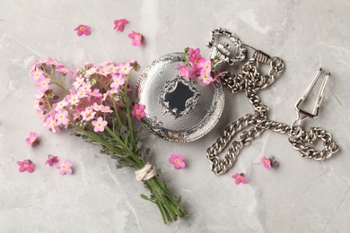 Photo of Beautiful Forget-me-not flowers and pocket watch on grey table, flat lay