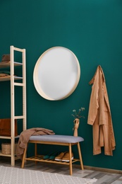 Round mirror on green wall in stylish hallway interior