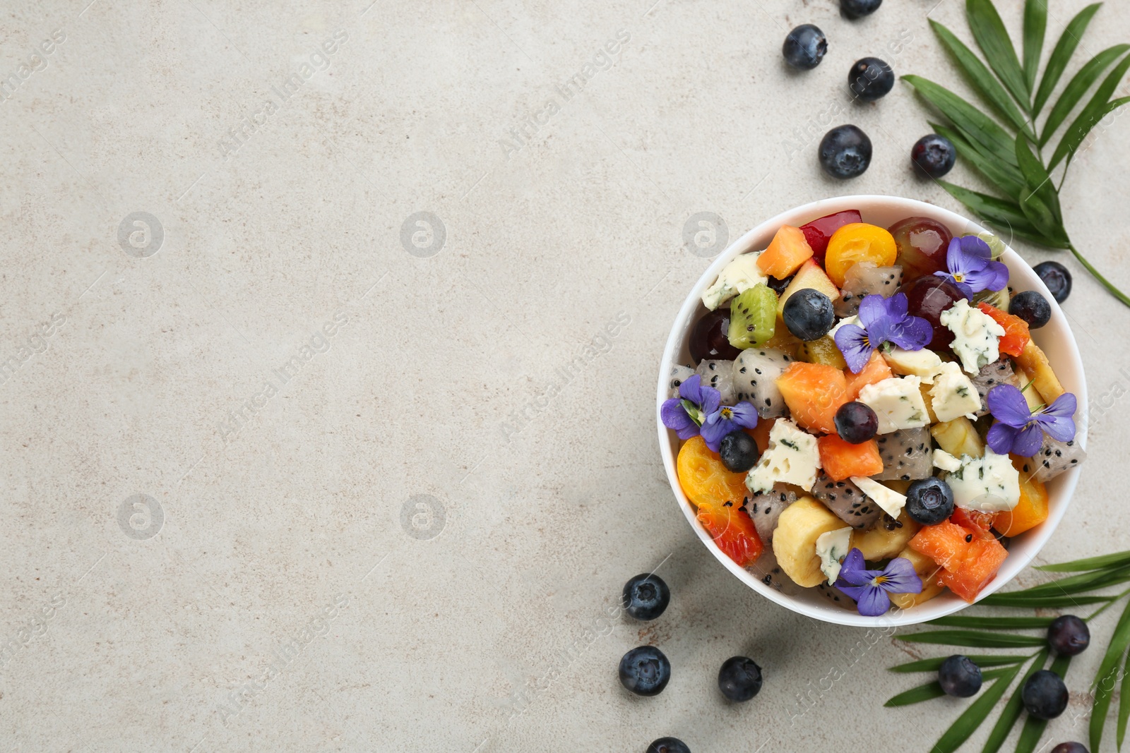 Photo of Delicious exotic fruit salad on light grey table, flat lay. Space for text