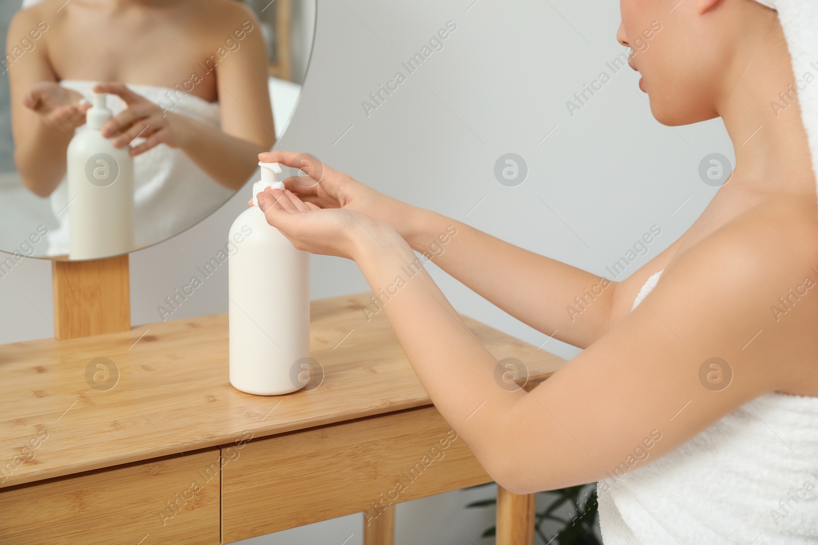 Photo of Young woman applying body cream on hands in bathroom, closeup