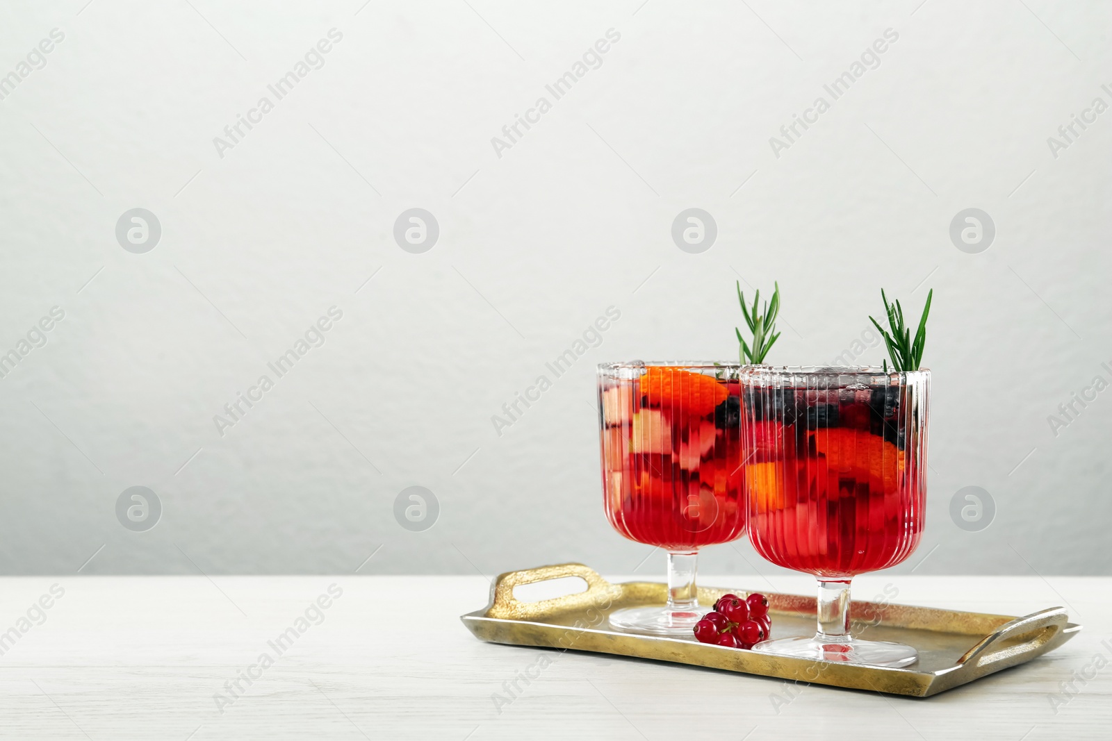 Photo of Glasses of Red Sangria on white wooden table against light grey background. Space for text