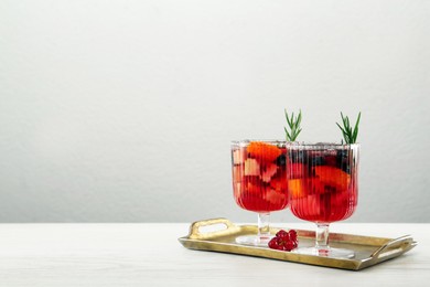 Photo of Glasses of Red Sangria on white wooden table against light grey background. Space for text