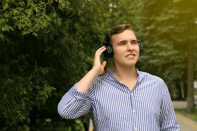 Photo of Handsome young man with headphones outdoors on sunny day