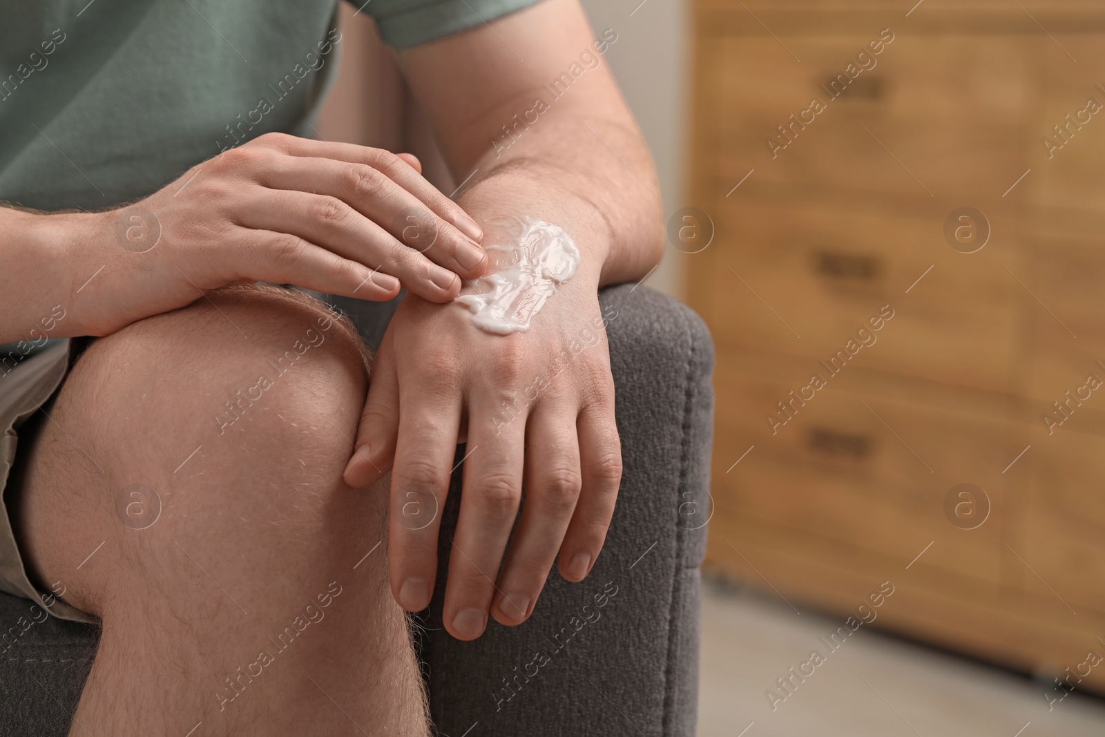 Photo of Man applying ointment onto his hand indoors, closeup. Space for text