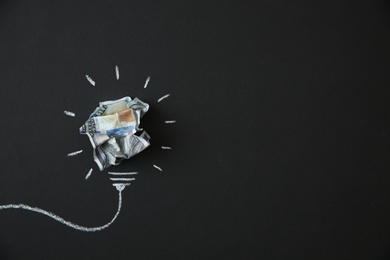 Photo of Composition with crumpled money as lamp bulb and space for text on black background