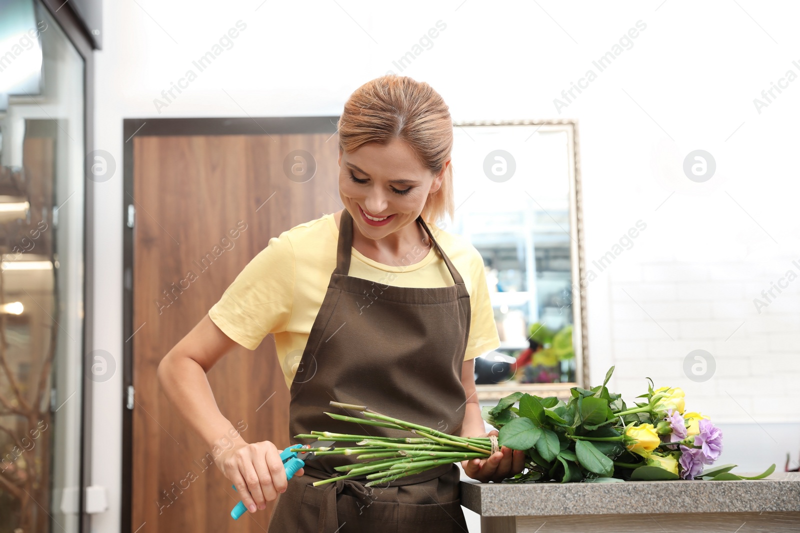 Photo of Female florist making beautiful bouquet in flower shop