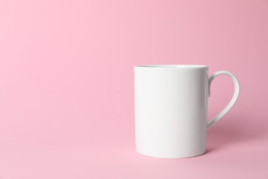 Photo of One white ceramic mug on pink background. Space for text