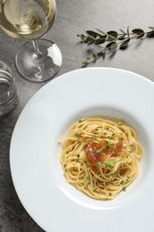 Photo of Tasty spaghetti with prosciutto and microgreens served on grey table, flat lay. Exquisite presentation of pasta dish