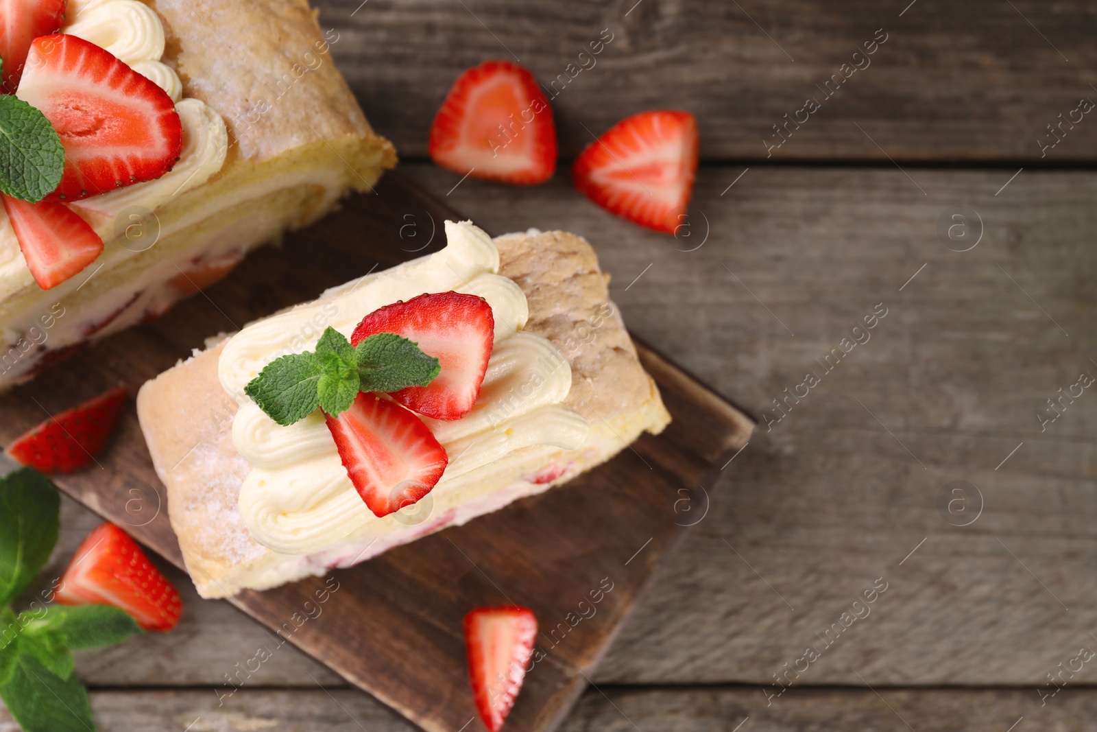 Photo of Pieces of delicious cake roll with strawberries and cream on table, top view. Space for text