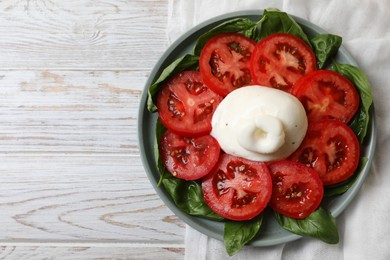 Delicious burrata cheese with tomatoes and basil on white wooden table, top view. Space for text