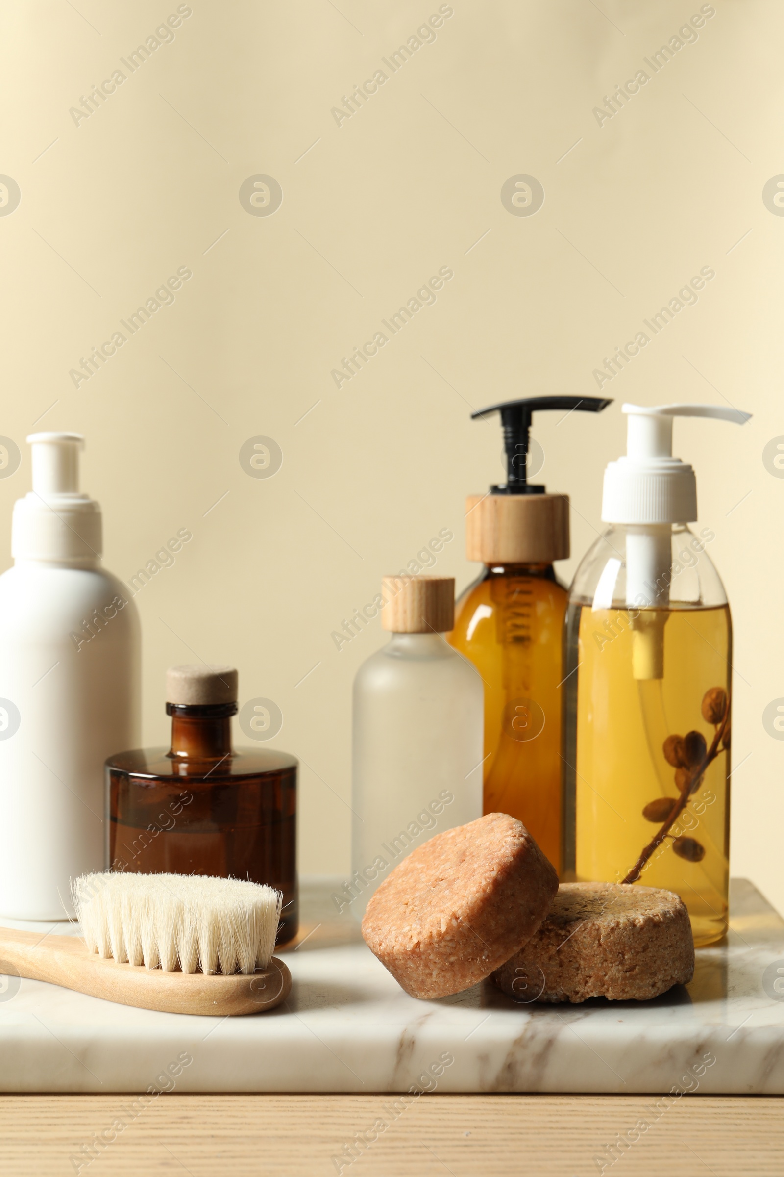 Photo of Different bath accessories on wooden table against beige background