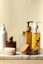 Different bath accessories on wooden table against beige background