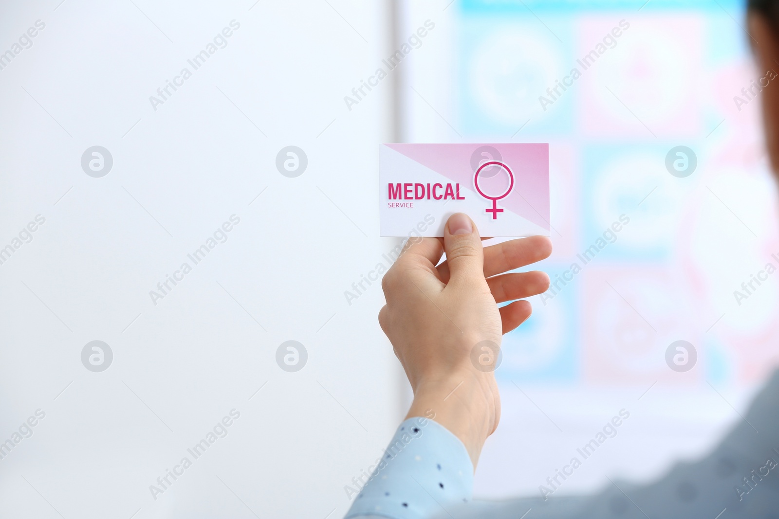 Photo of Girl holding medical business card indoors, closeup. Women's health service