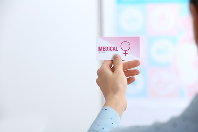 Girl holding medical business card indoors, closeup. Women's health service