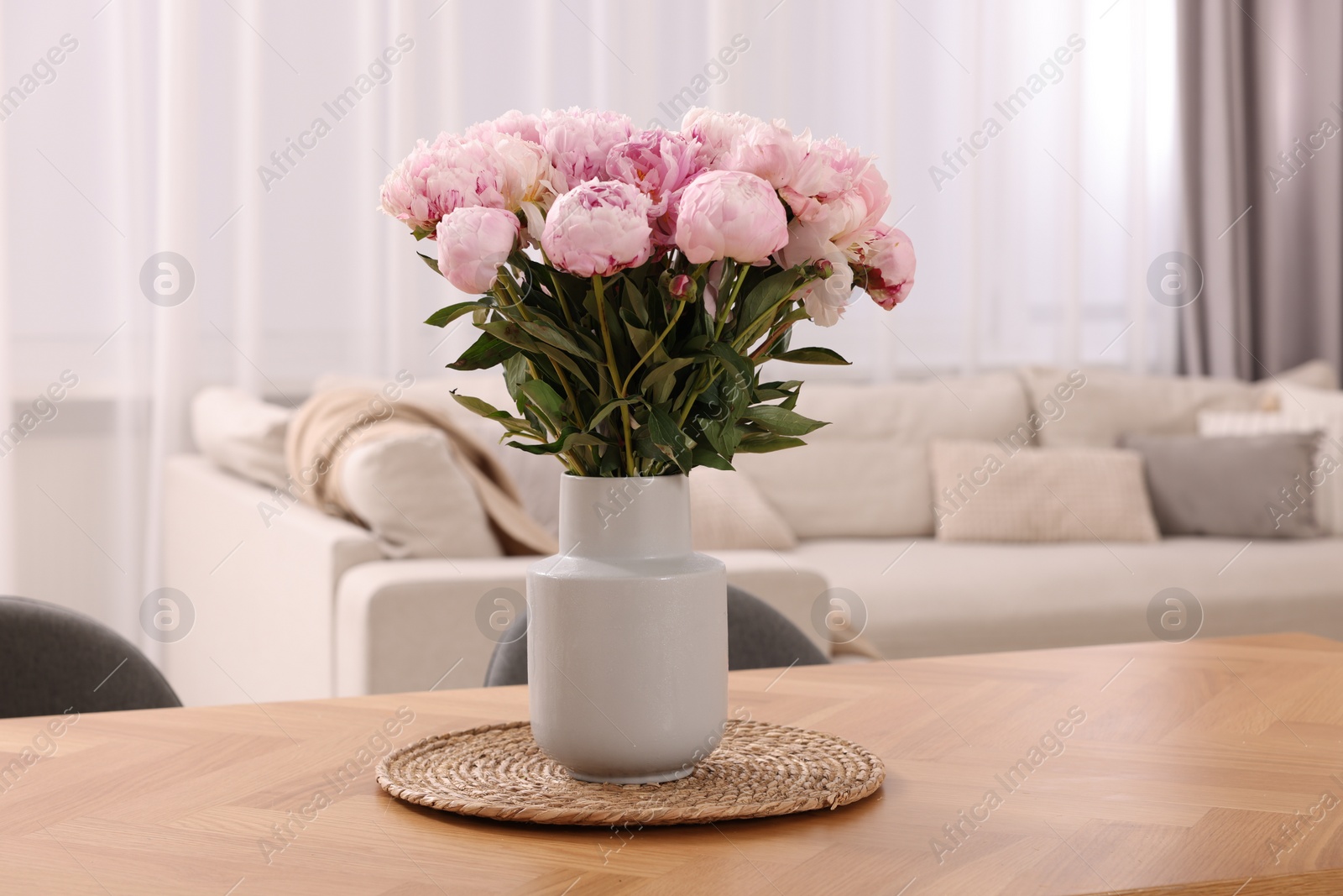 Photo of Vase with pink peonies on wooden table in dining room